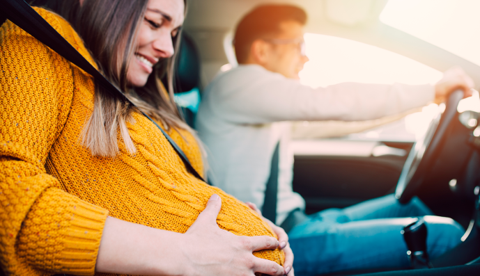Foto: Schwangere Frau und Ehemann fahren im Auto zur Geburtsklinik
